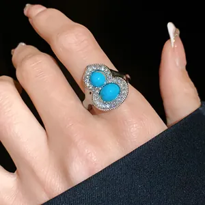 Close-up of elegant gourd-shaped ring with turquoise stones and shimmering rhinestones