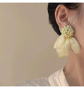 Primo piano di orecchini floreali con perline e petali in organza gialla indossati