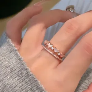 Detailansicht eines roségoldenen Herzrings mit Perlmutt und Zirkonia am Finger der Frau