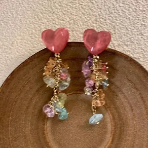 Primo piano di orecchini colorati a cuore con nappe su fondo legno