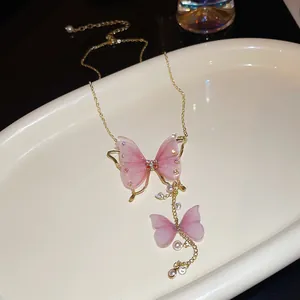 Dettaglio della collana dorata con farfalle in tulle rosa, perle e strass brillanti