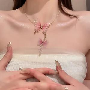 Dettaglio di una collana con farfalla in tulle rosa, perle e strass su una modella