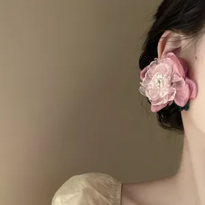 Vista dettagliata di un elegante orecchino a fiore in tessuto rosa su una modella