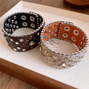 Dettaglio di due braccialetti in pelle vintage decorati con strass colorati e borchie