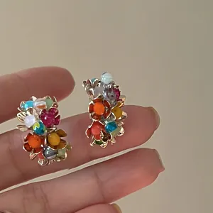 Dettaglio ravvicinato di orecchini a lobo a forma di fiore colorati con perni in argento