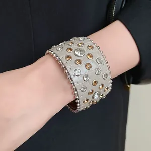 Dettaglio ravvicinato di un bracciale in pelle vintage con strass e borchie in argento