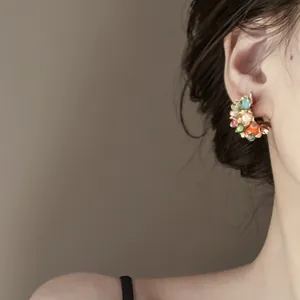 Dettaglio di orecchini floreali colorati stile dopamina indossati all'orecchio, elegante