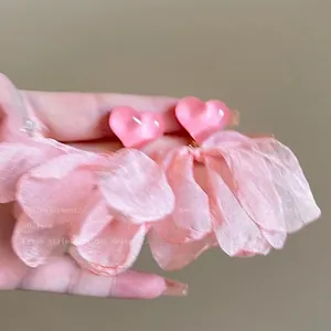 Primo piano di orecchini a cuore rosa con nappe di fiori in tessuto