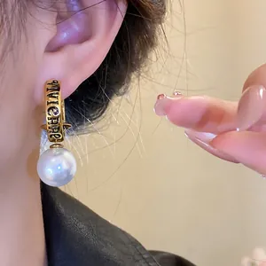 Vintage gold Saturn hoop earrings with faux pearl drop and engraved lettering detail.