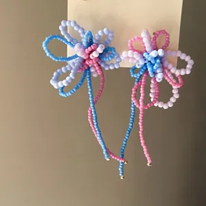 Dettaglio ravvicinato di orecchini a fiore con perline colorate e lunghe nappe di perle