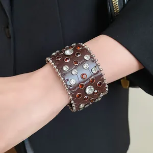 Dettaglio di un bracciale in pelle vintage con strass e borchie al polso