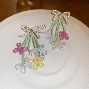 Dettaglio degli orecchini a nappa con fiori e fiocchi in perline colorate.