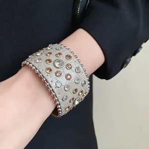 Primo piano di un bracciale in pelle retrò con strass e motivo coccodrillo al polso