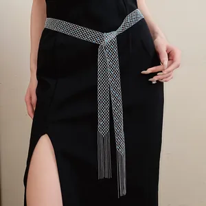 Dettaglio ravvicinato di cintura in maglia argento con strass blu e frange su abito