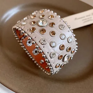Vista dettagliata di un bracciale in pelle a motivo coccodrillo con strass e borchie