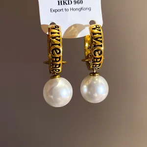 Detail view of gold-toned Vivienne-style hoop earrings featuring elegant white pearls.