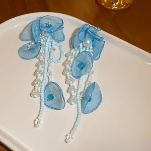 Dettaglio ravvicinato degli orecchini a fiore in tessuto blu con eleganti perle