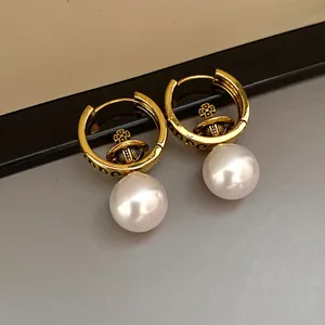 Close-up of vintage golden Saturn orb hoop earrings with elegant white pearl drops