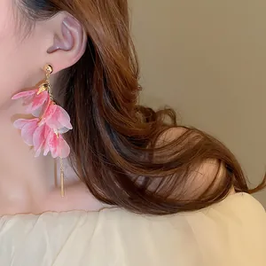 Dettaglio degli orecchini con nappe di petali rosa indossati da modella