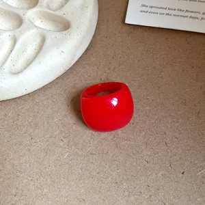 Primo piano di un anello ovale in resina rossa minimalista su superficie rustica