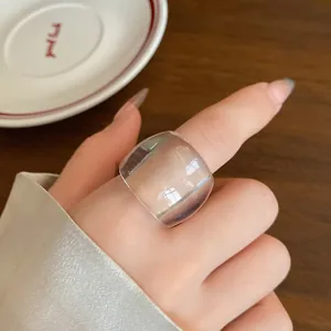 Primo piano di un anello ovale in resina trasparente minimalista sull'indice.