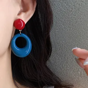 A close-up shot of vintage resin hoop earrings in bold red and blue dopamine colors.