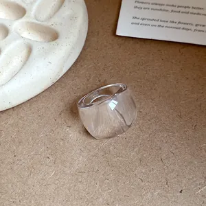 Primo piano dettagliato di un anello ovale in resina trasparente su superficie.