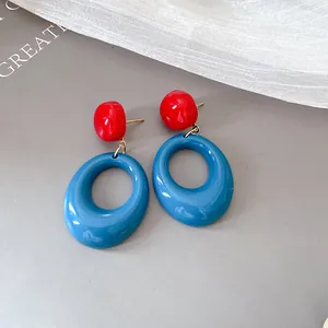 Detailed view of retro red and blue resin oval drop earrings with silver needles