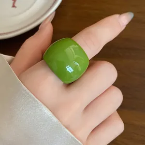 Dettaglio ravvicinato di un anello in resina verde vibrante indossato sul dito indice