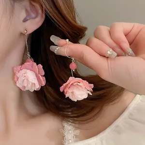 Primo piano di orecchini con nappe a petali di rosa in tessuto rosa su modella