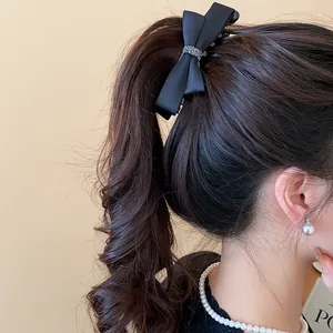 Vue détaillée d'une élégante pince à cheveux noeud en satin noir avec détails en cristal