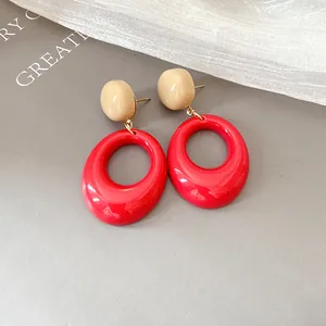 Close-up of vintage resin oval drop earrings in red and beige retro color scheme