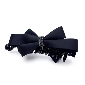 Pince à cheveux banane élégante en satin noir avec un nœud et des strass scintillants.