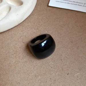 Anello in resina nera spessa con finitura lucida in un ambiente minimalista