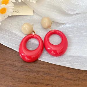 Close-up of vintage red resin oval drop earrings on a textured background