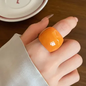 Primo piano di un audace anello in resina arancione con finitura lucida sulla mano