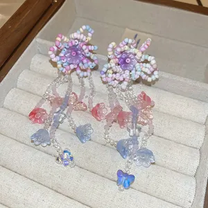 Dettaglio orecchini a fiore con perline colorate e pendenti a nappa con farfalle