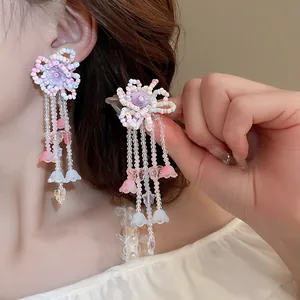 Dettaglio di orecchini floreali stile dopamina con nappine e perline a forma di mughetto.
