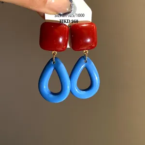 Detailed view of retro resin drop earrings in vibrant red and blue with glossy finish
