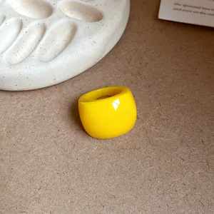 Dettaglio di un anello in resina giallo vivace con finitura lucida e design minimalista.