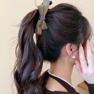 Vue détaillée d'une élégante pince à cheveux en satin vert olive sur cheveux bruns bouclés