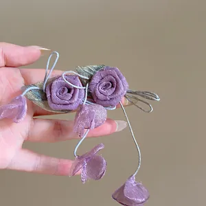 Vista dettagliata di orecchini a fiore in tessuto viola con lunghe nappe e foglie