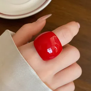 Vista dettagliata di un anello in resina rossa lucida al dito, accessorio moda minimale