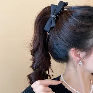 Vue détaillée d'une élégante pince à cheveux en satin noir portée sur une queue de cheval