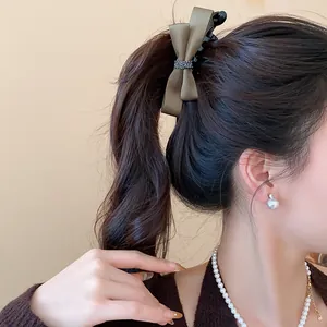 Élégante pince à cheveux avec nœud en satin vert foncé sur une queue de cheval haute