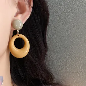 Close-up detail of a vintage style yellow resin oval pendant earring on a model ear