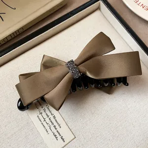 Détail de pince à cheveux banane en satin marron avec centre élégant en strass et tissu texturé