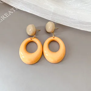 Close-up of retro resin oval drop earrings in beige and orange tones