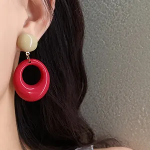 Detailed view of retro resin drop earrings with red and beige pendant worn on ear