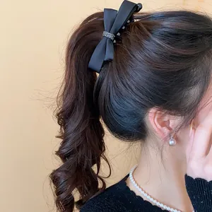 Élégante barrette à nœud en satin noir portée sur une queue de cheval pour un look chic.